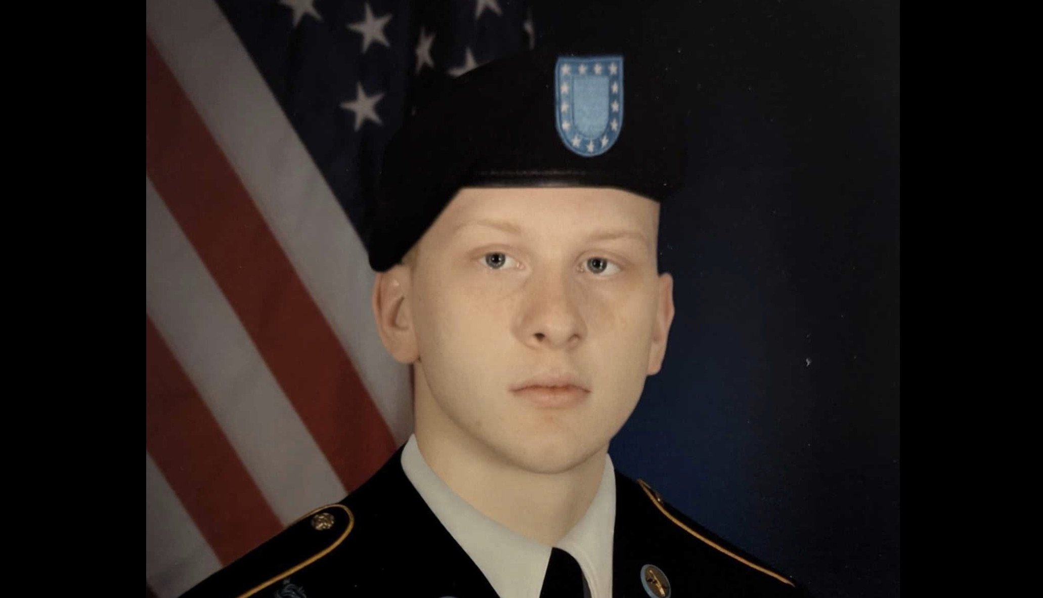 Portrait of a young soldier in uniform, standing against a backdrop of the American flag, showcasing military pride and commitment.