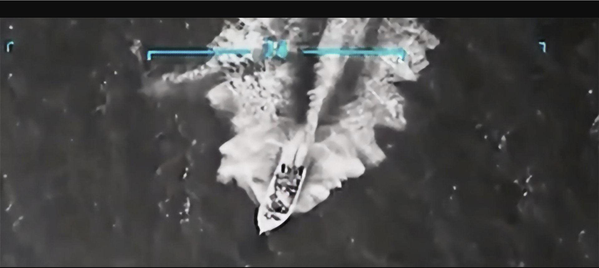Aerial view of a speedboat navigating through water, creating waves and spray, captured in a high-contrast monochrome image.