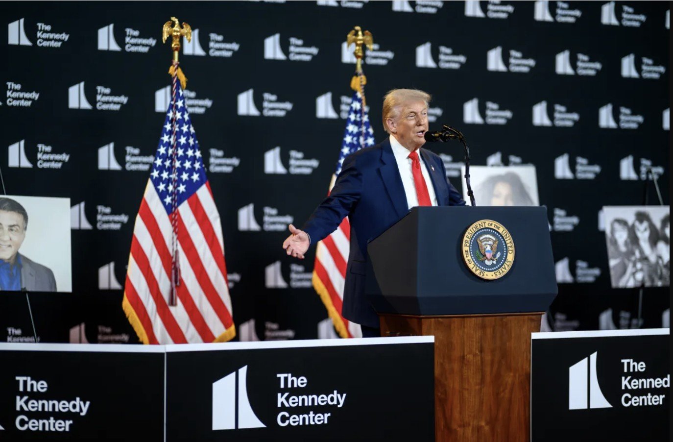 Donald Trump speaks at an event at The Kennedy Center, with American flags and portraits in the background.
