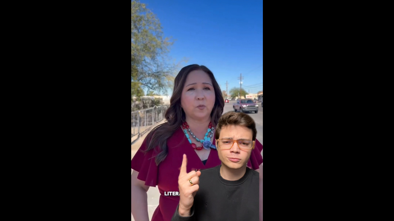 A woman in a red dress speaks outdoors while a young man gestures, highlighting a conversation on a sunny day.