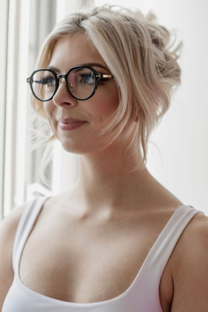 A woman wearing glasses looking out a window