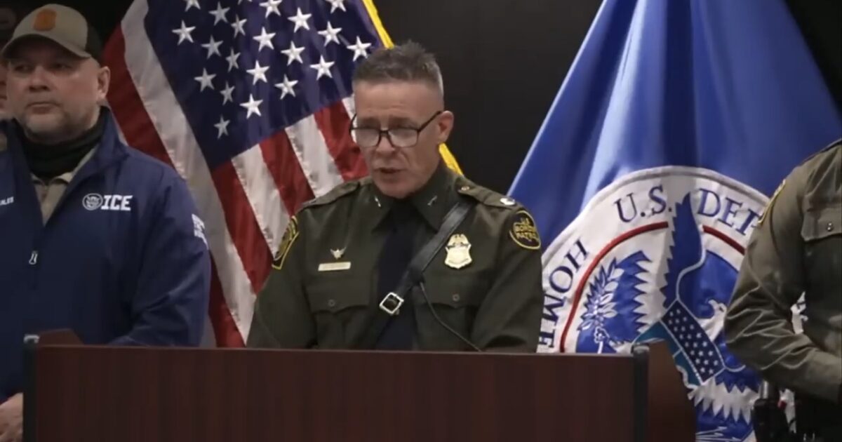 Law enforcement officials hold a press conference with U.S. flags in the background, discussing immigration enforcement and public safety measures.