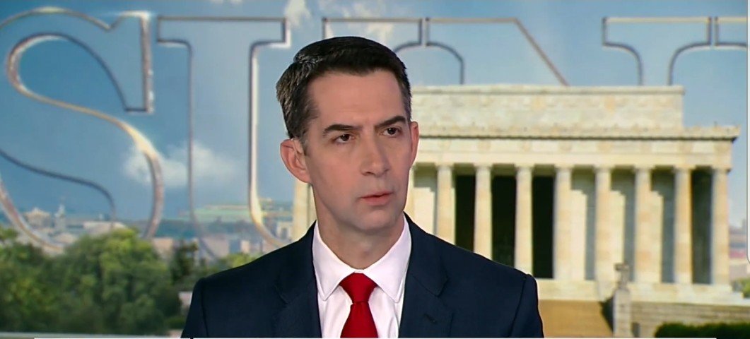 Tom Cotton speaking during a televised interview with the Lincoln Memorial in the background, showcasing a political discussion setting.