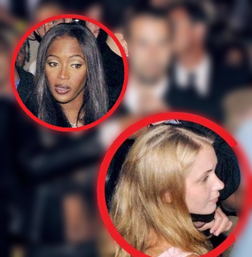 Two women at a crowded event, one with long dark hair and the other with light blonde hair, both appearing engaged in conversation.