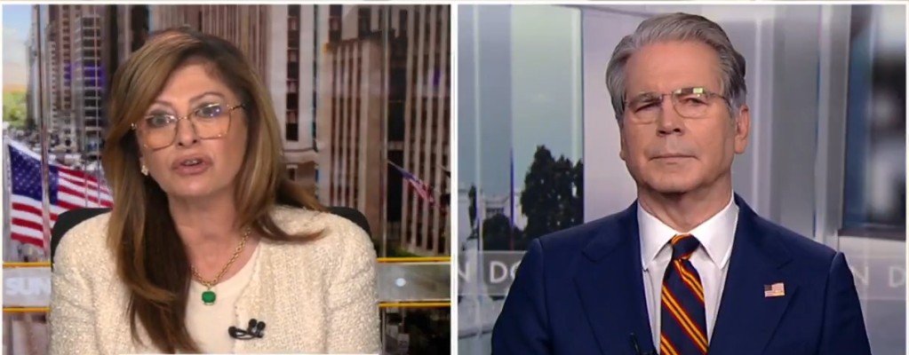 News segment featuring two presenters discussing current events, with American flags visible in the background.