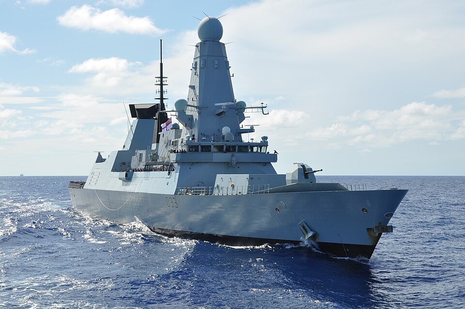 Modern naval warship sailing through open waters under a clear sky, showcasing advanced military technology and design.