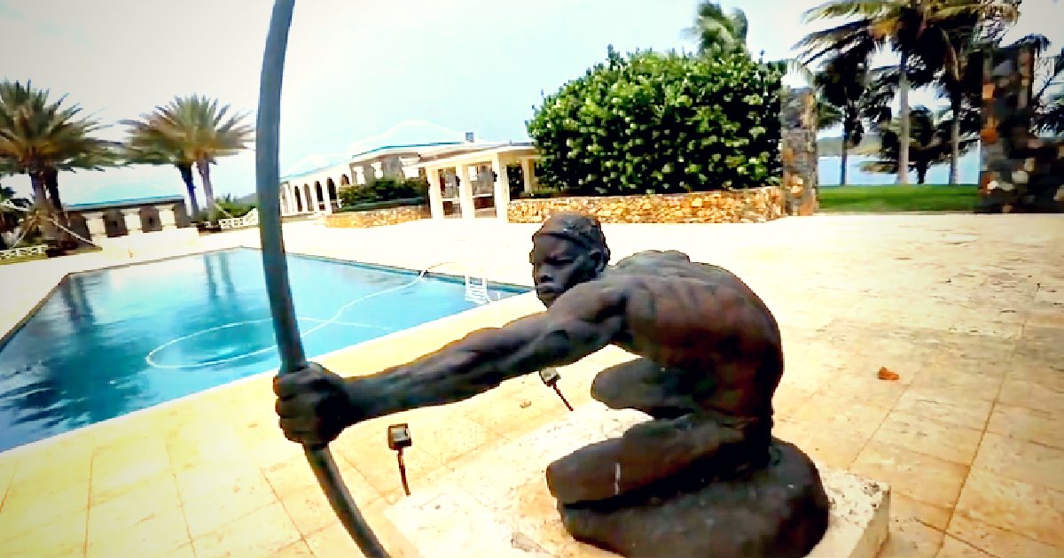 Bronze statue of an archer poised near a swimming pool, surrounded by palm trees and a luxurious villa in the background.