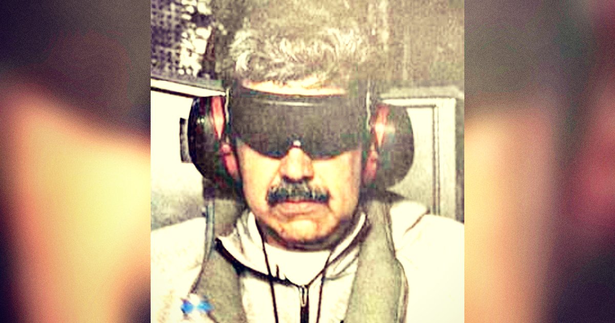 Man wearing sunglasses and headphones, seated in a cockpit, focused on an aviation simulator or training environment.