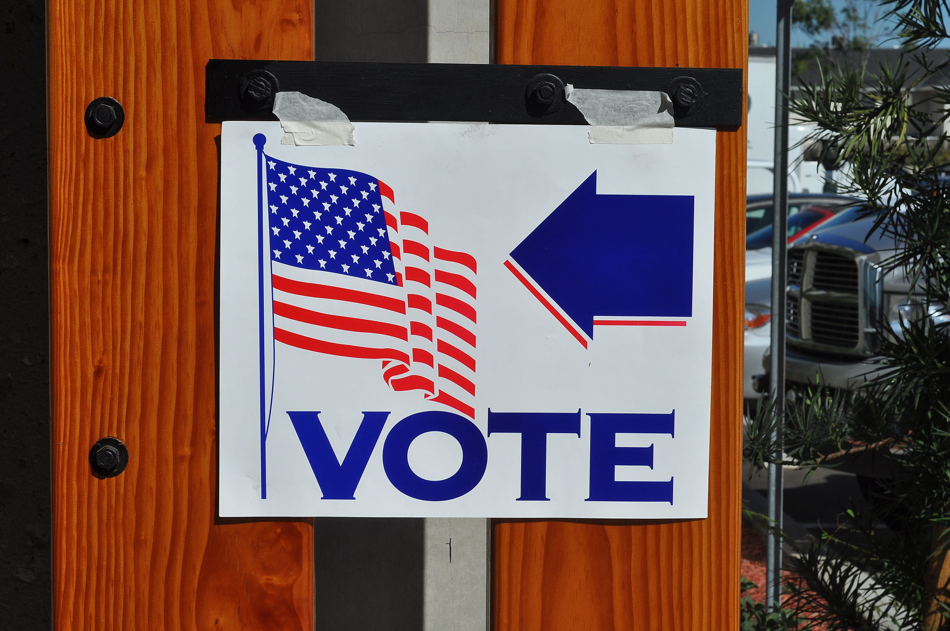 Vote sign with an American flag and an arrow pointing left, indicating the direction to the polling place.