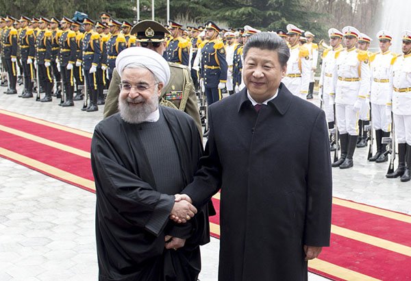 Iranian President Hassan Rouhani and Chinese President Xi Jinping shake hands during a formal welcome ceremony with military honor guards in the background.