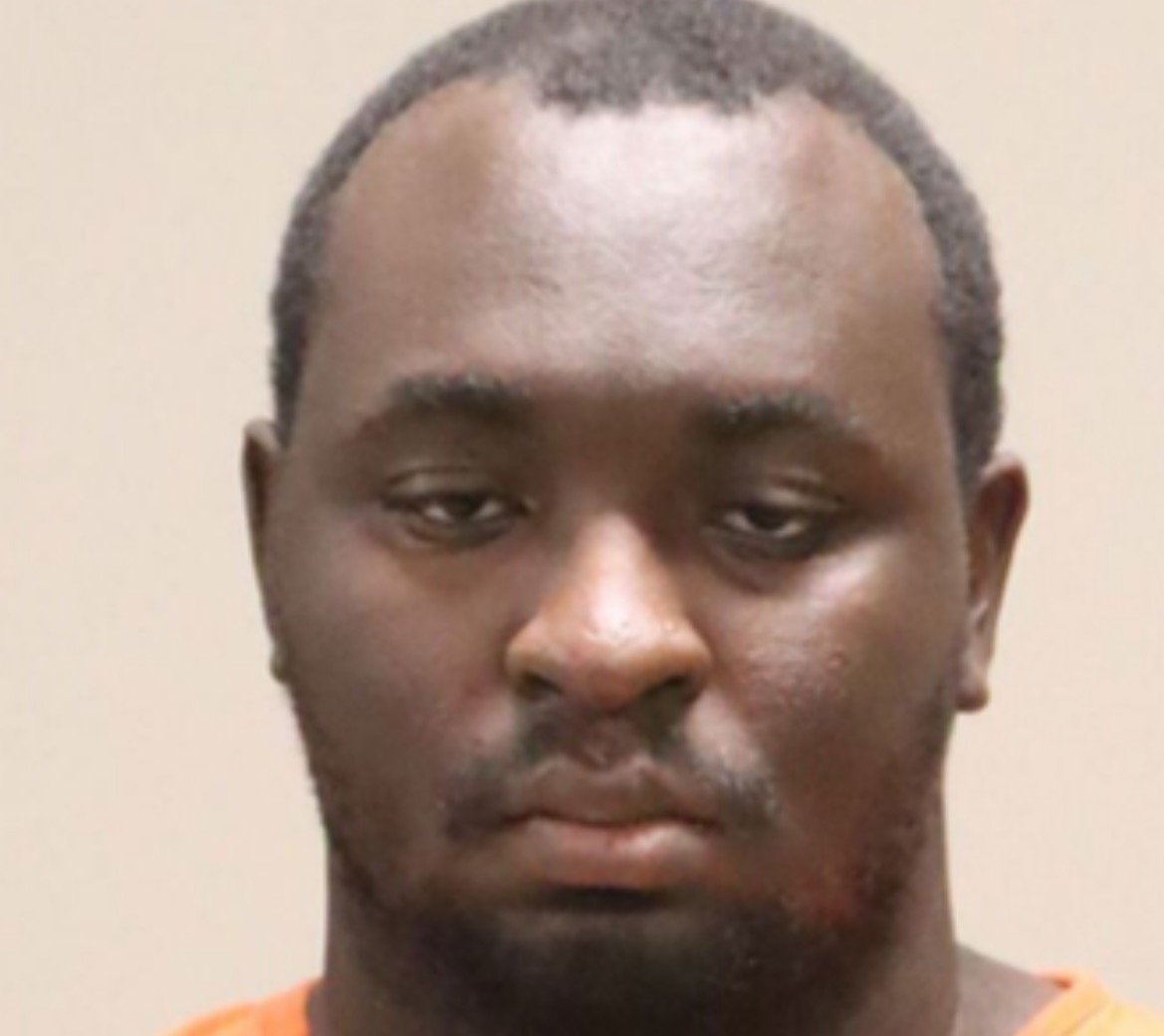 Mugshot of a man wearing an orange jumpsuit with a neutral expression against a plain background.