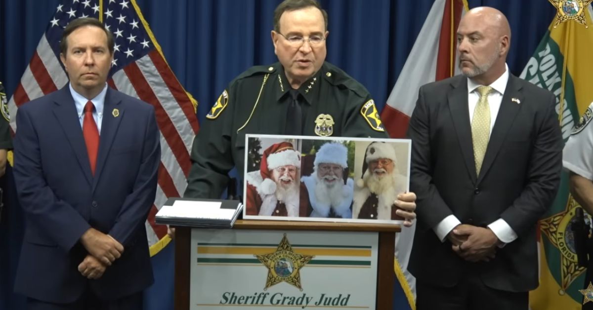 Sheriff Grady Judd discusses a case while holding a photo of three Santa Claus figures during a press conference in Florida.