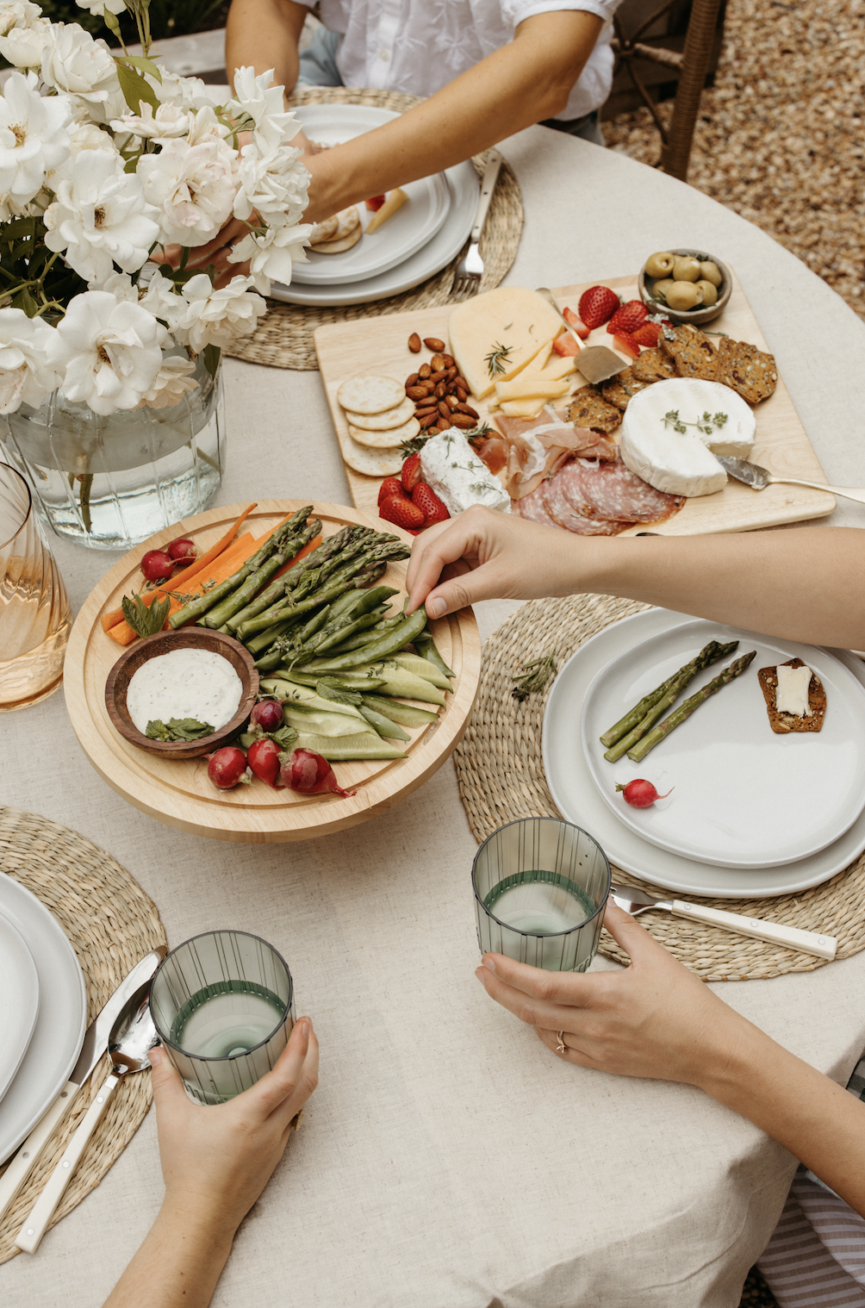 Women practicing mindful eating rituals at outdoor dining table.