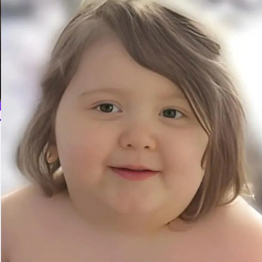Close-up portrait of a smiling toddler with short brown hair against a soft blurred background.