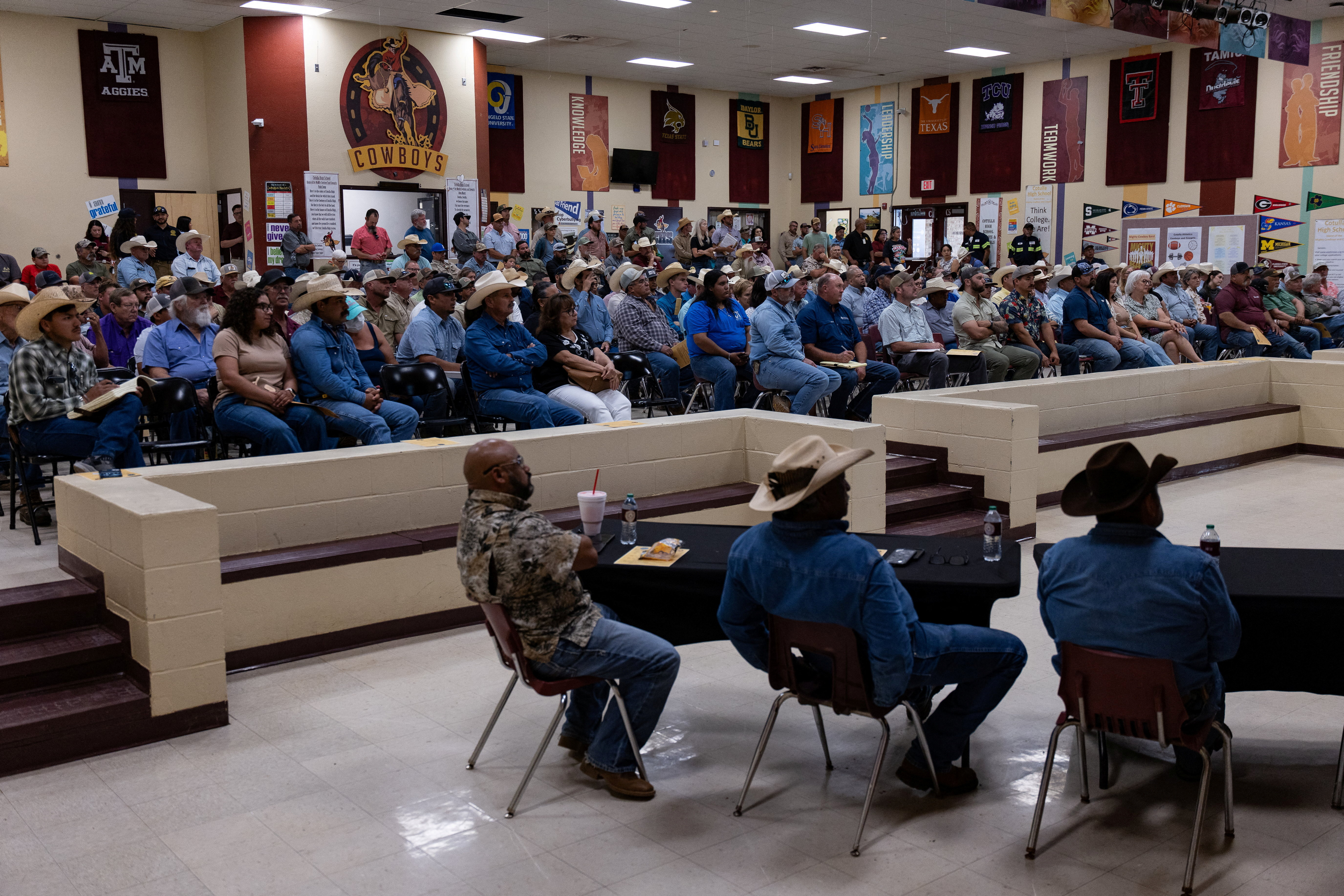 Crowd of people seated at an informational meeting inside Cotulla High School in Texas