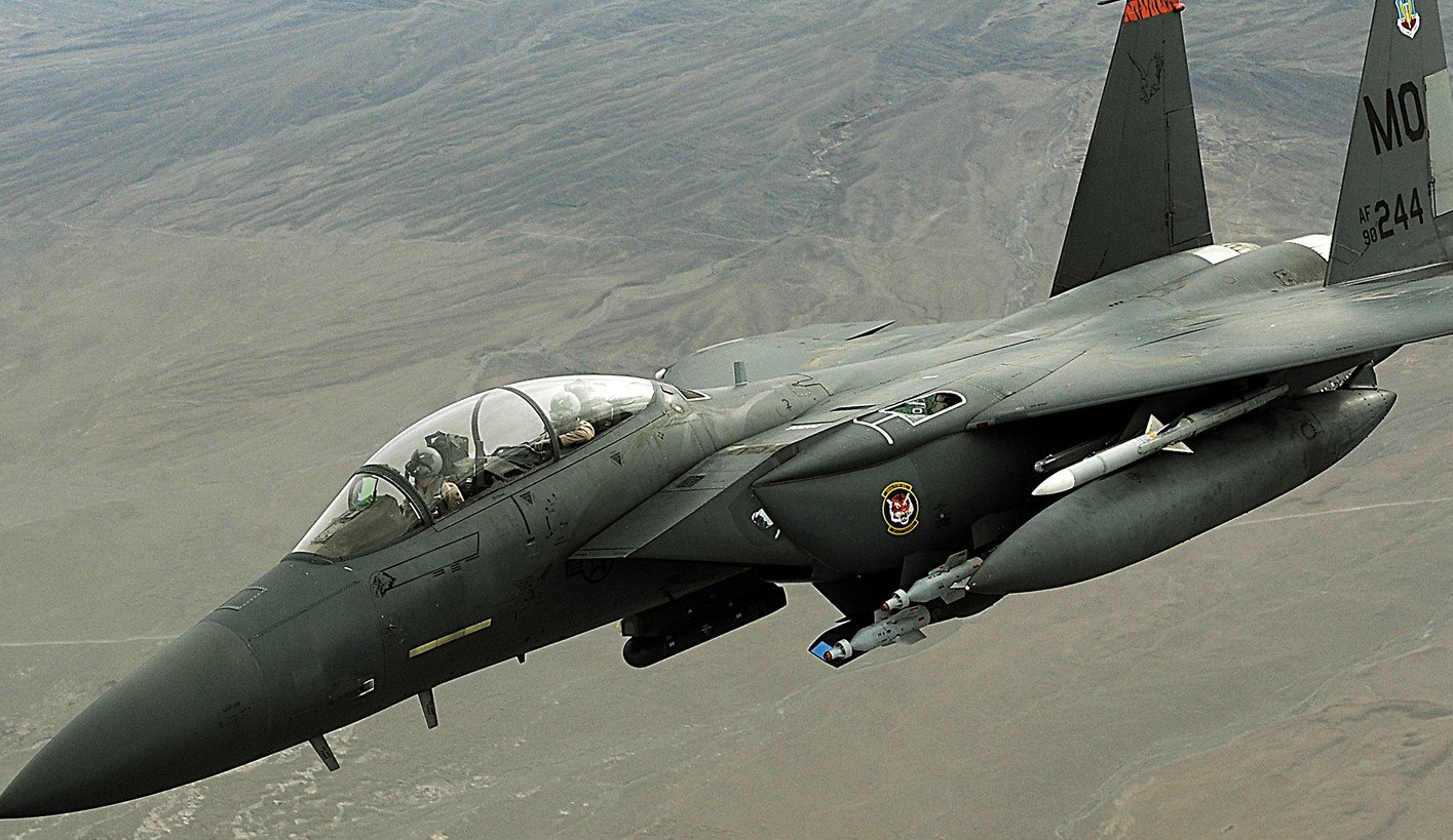 F-15 fighter jet in flight showcasing military aviation technology and capabilities against a mountainous backdrop.