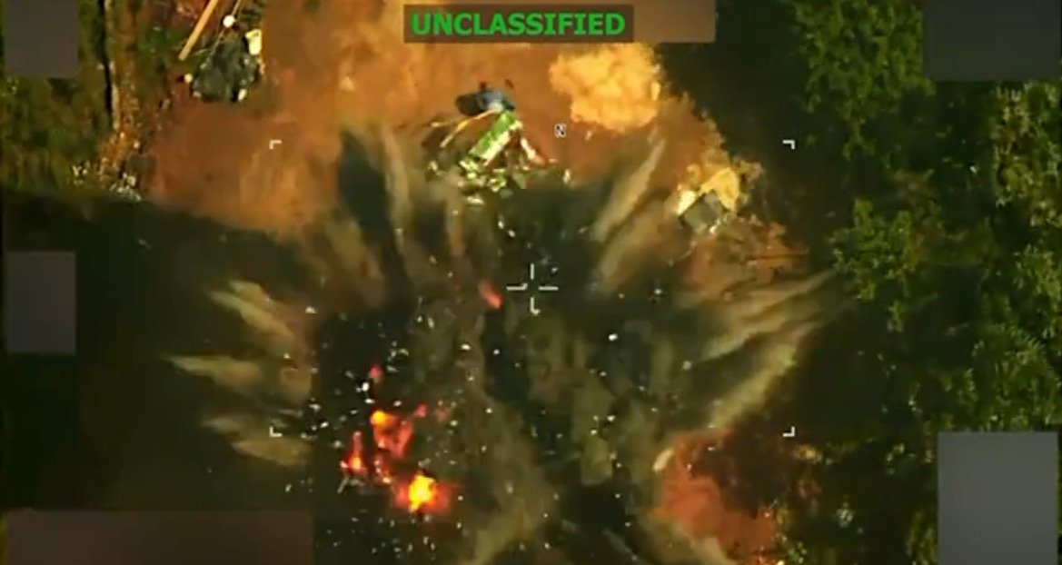 Aerial view of an explosion occurring in a wooded area, showcasing debris and smoke emanating from the blast site.