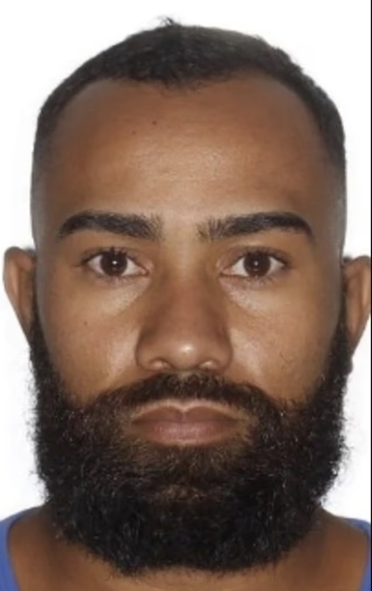 Close-up ID photo of a man with a short haircut and full dark beard against a white background.