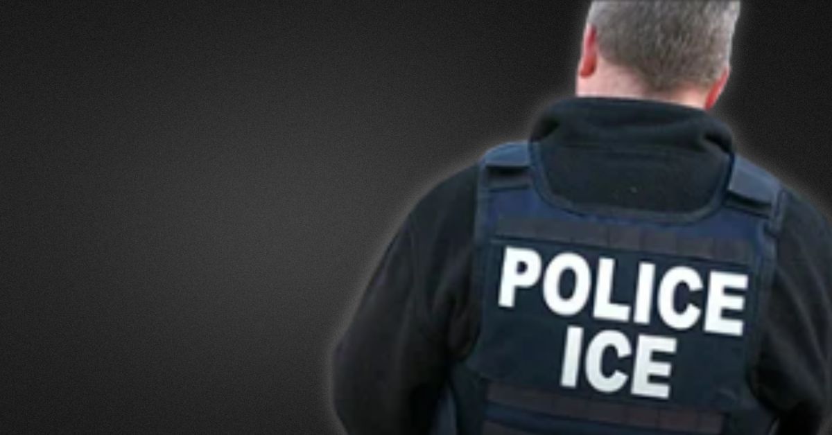 An officer wearing a black tactical vest labeled Police ICE stands with their back to the camera against a dark background.