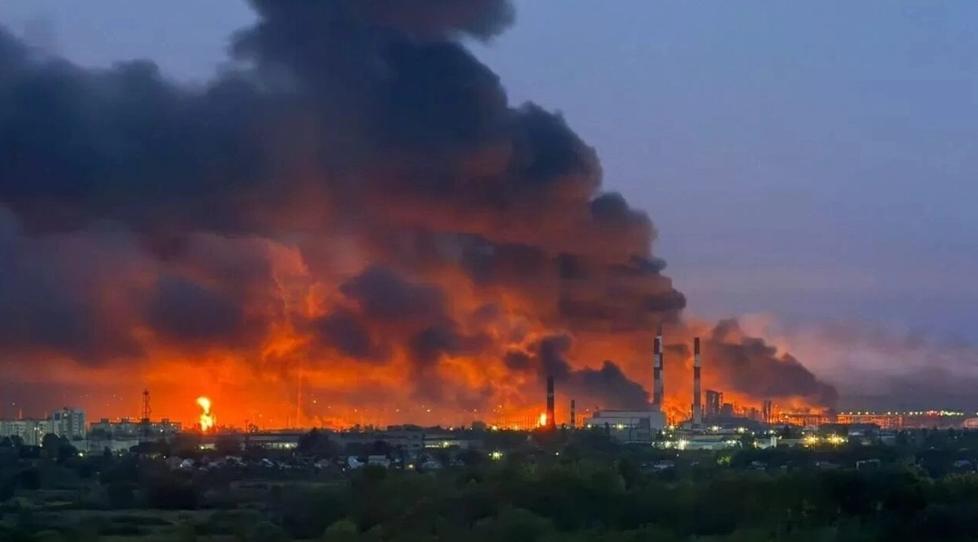 Industrial fire releasing thick black smoke and flames into the sky, highlighting environmental hazards and safety concerns in urban areas.