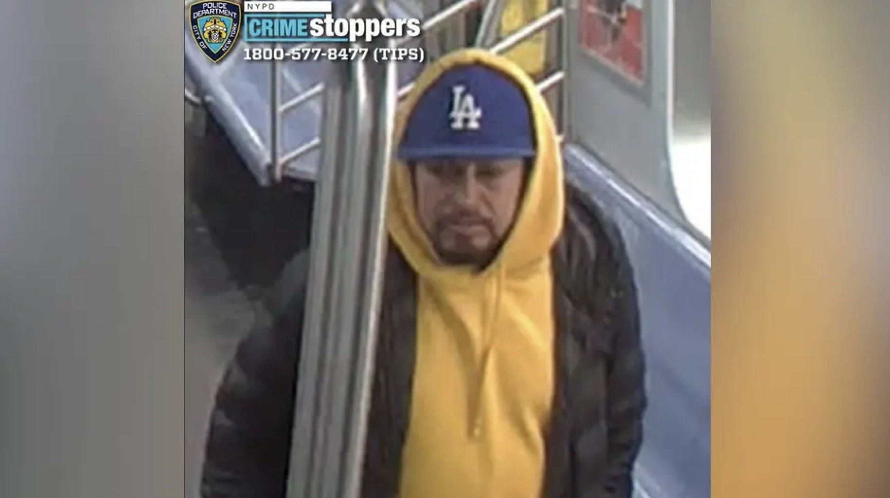 Surveillance image of a man wearing a yellow hoodie and a blue cap on public transportation, sought by NYPD for questioning in a criminal investigation.