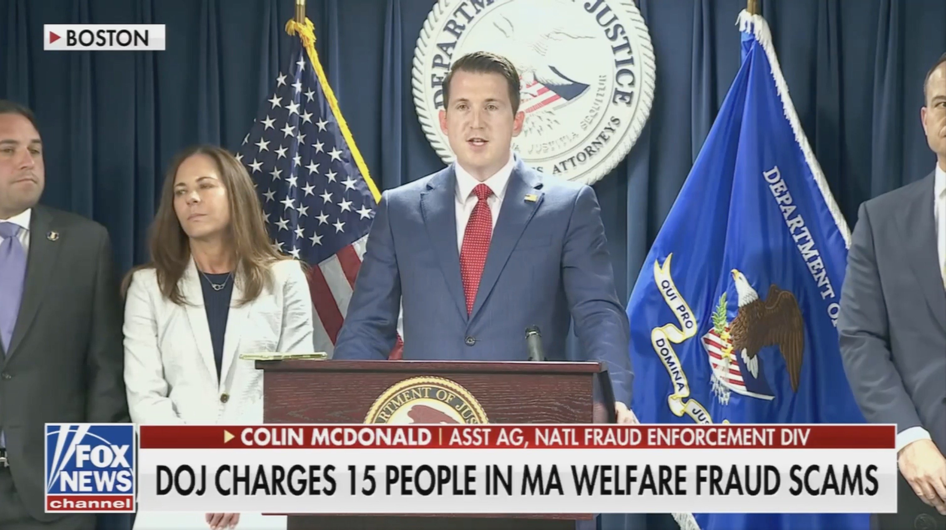 Press conference in Boston announcing DOJ charges against 15 individuals for welfare fraud scams, featuring Colin McDonald, Assistant Attorney General for National Fraud Enforcement Division.