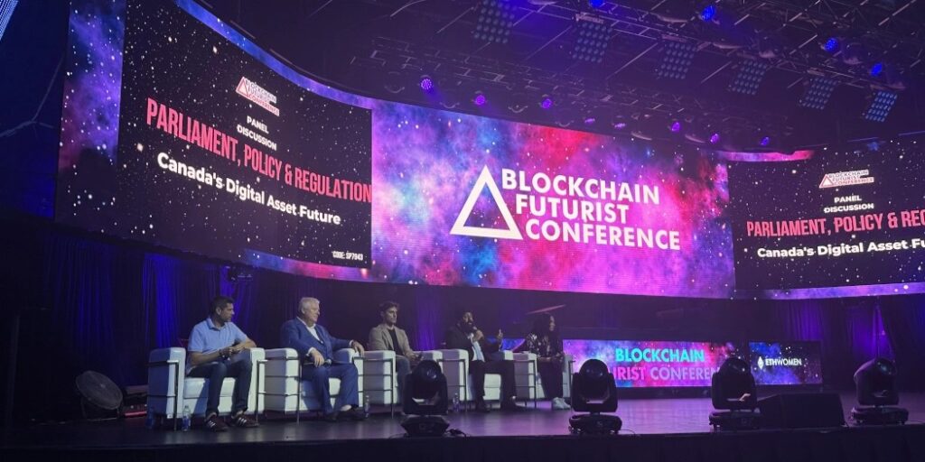 Panellists on stage under a large sreen.