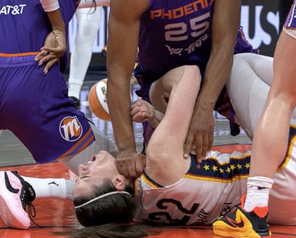 Intense moment during a women's basketball game, featuring players from the Phoenix team and a player from the opposing team on the court.