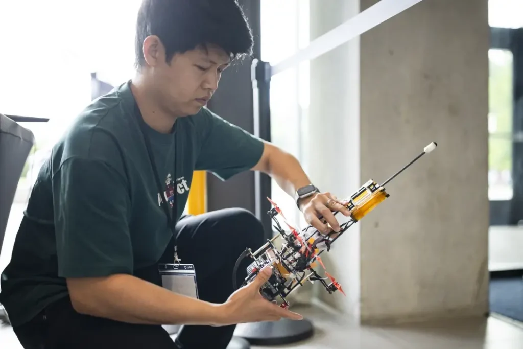 A man adjusts a small robot.