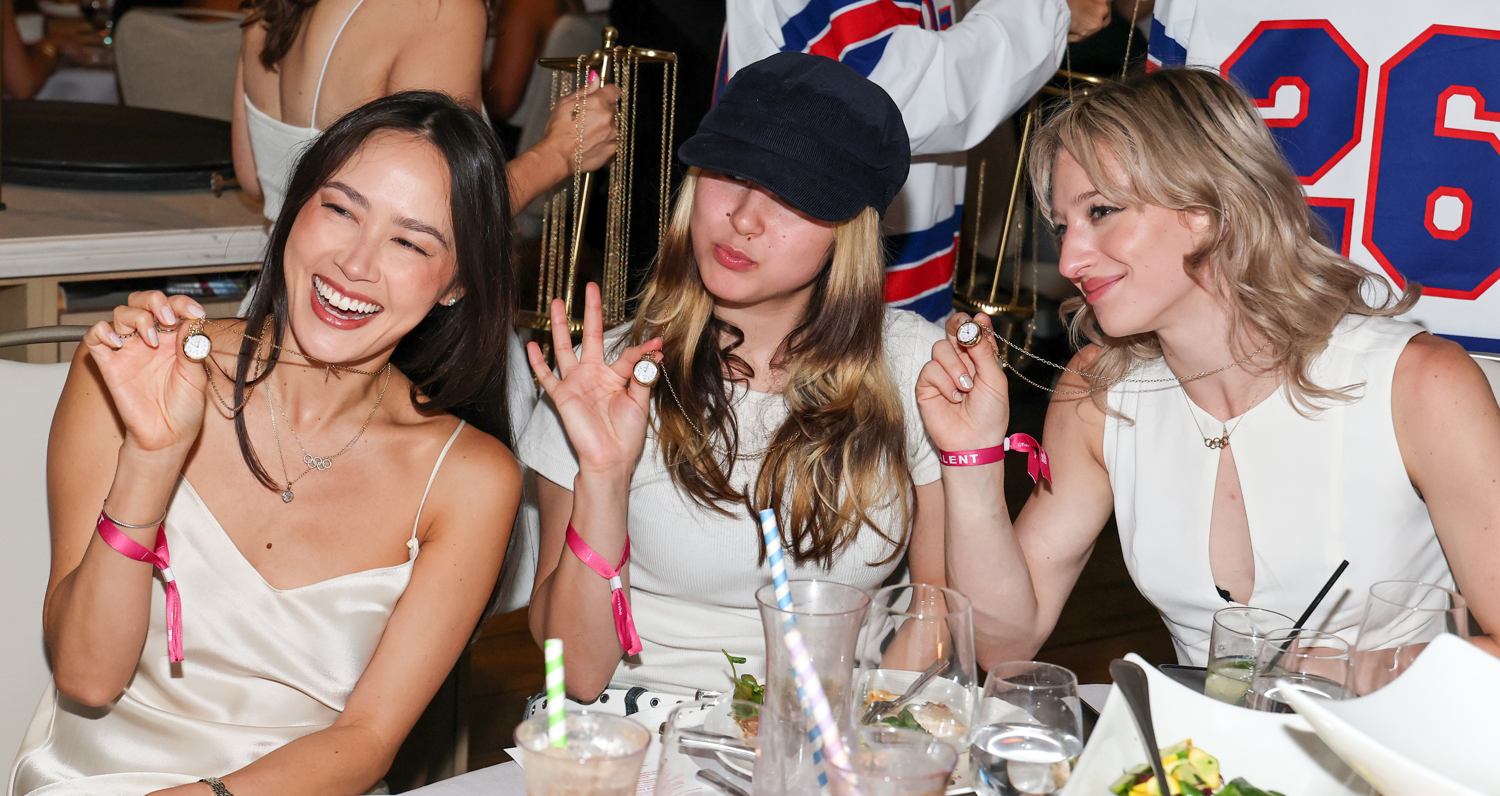 Figure skaters Madison Chock, Alysa Liu, and Amber Glenn wearing Shinola clock necklaces at a Las Vegas dinner