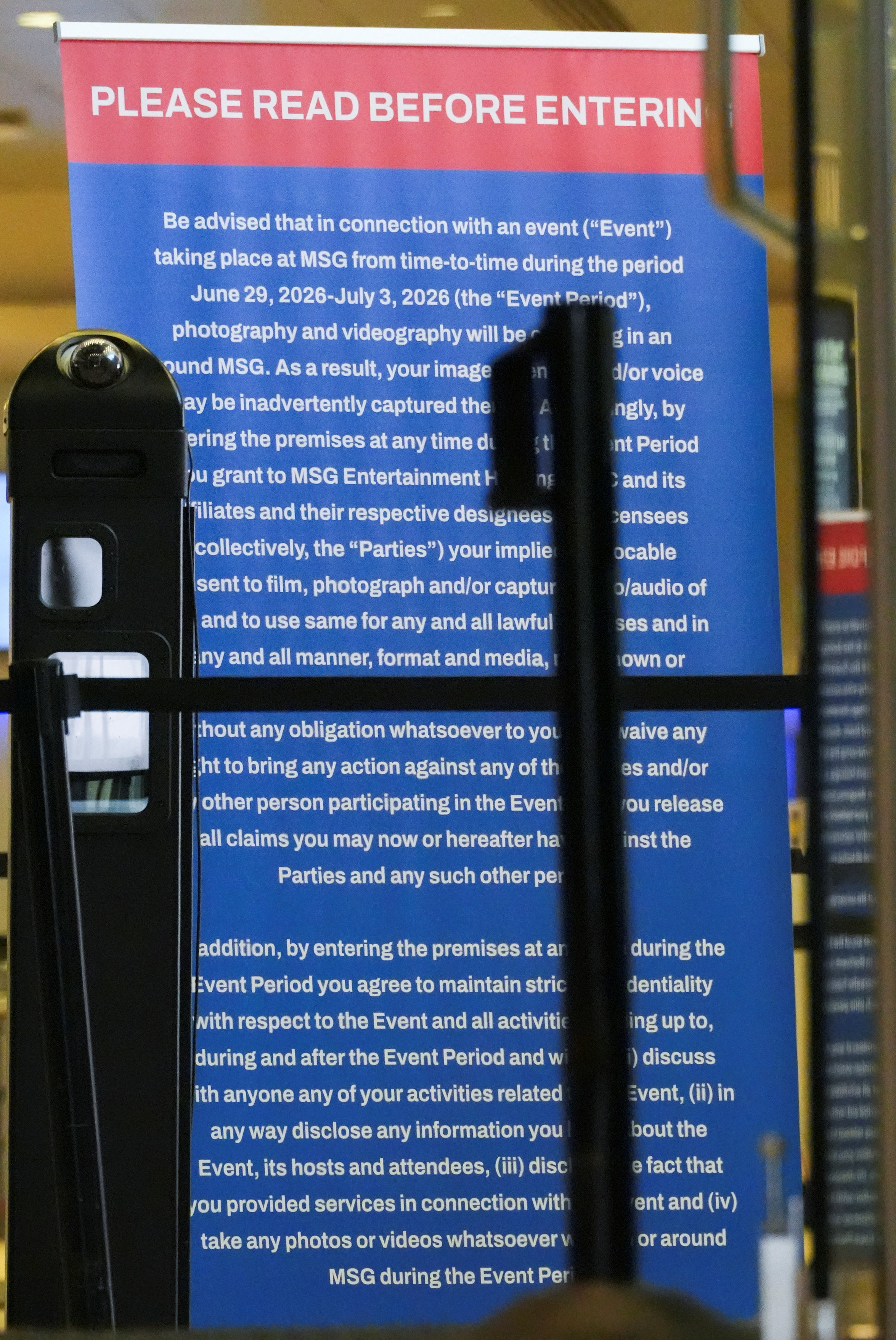 Blue and red banner sign reading 'Please Read Before Entering' posted at a Madison Square Garden entry, partially obscured by a stanchion.