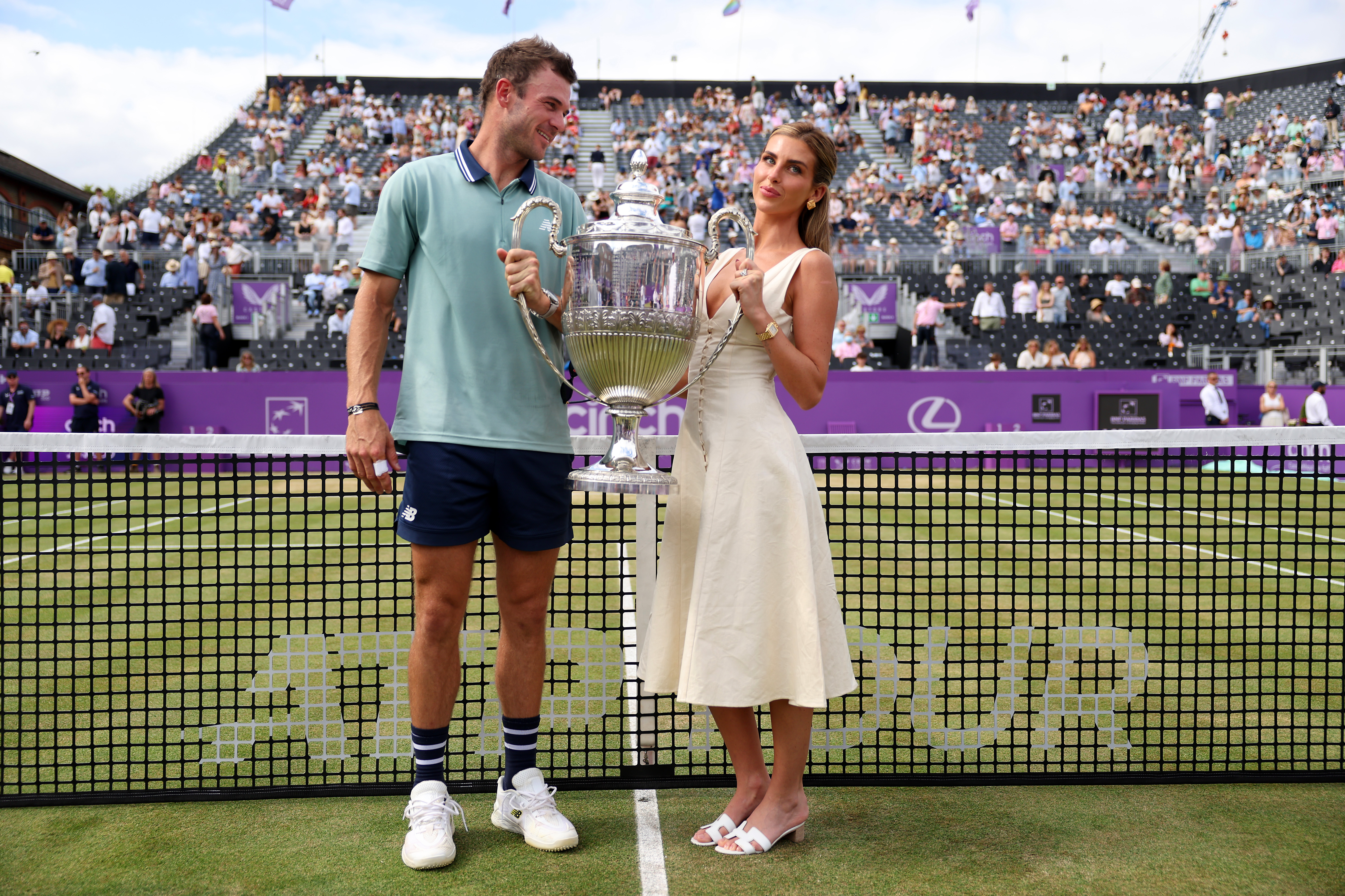 Tommy Paul and Paige Lorenze posing together with the cinch Championships 2024 winners trophy at The Queen's Club in London