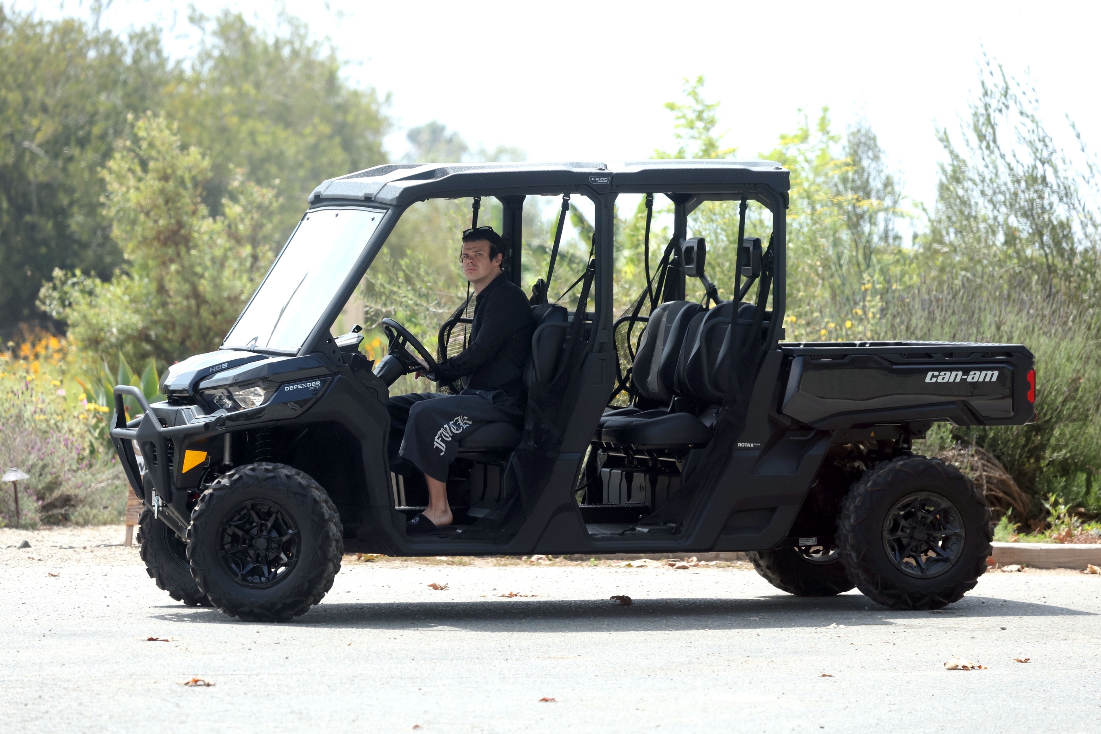 Yungblud carrying a Whole Foods bag next to a Can-Am Defender vehicle in Malibu, wearing Chrome Hearts slippers and cropped sweatpants