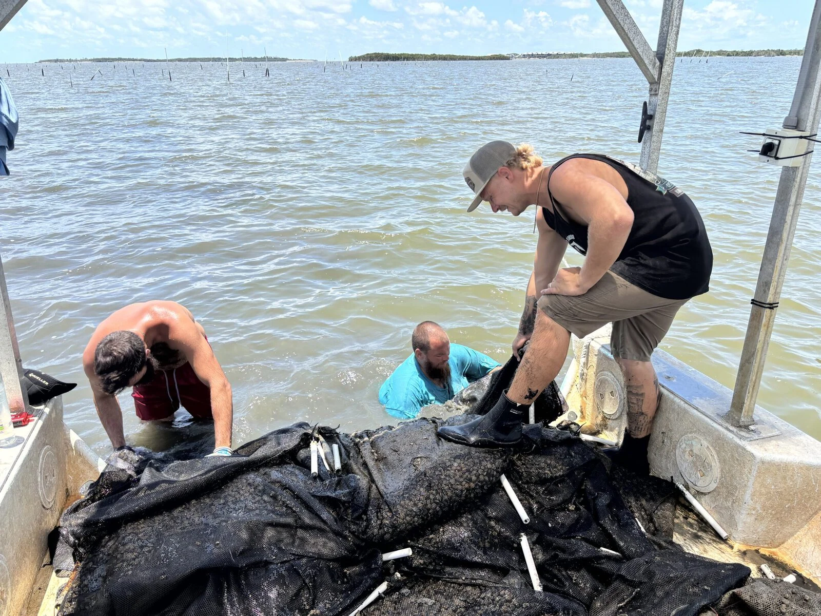 Three men are farming shellfish on a boat.