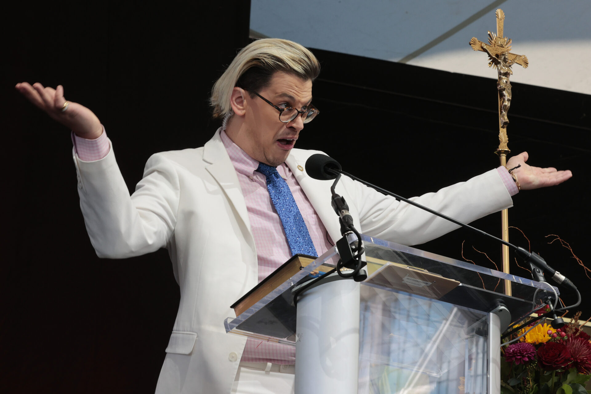 Milo Yiannopoulos speaking at a podium at the Bishops Enough Is Enough rally at the MECU Pavilion in Baltimore