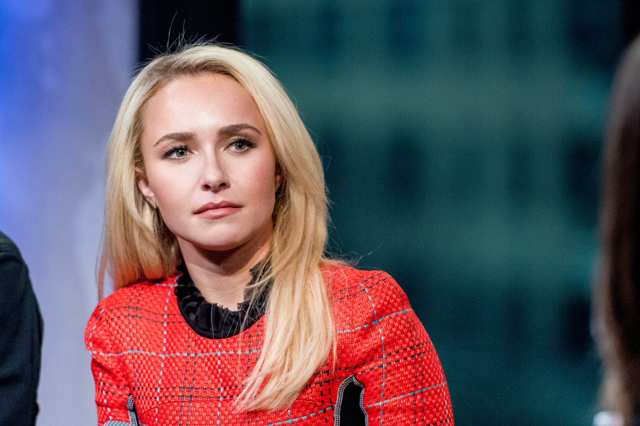 Blonde woman in a red tweed top sitting and looking off to the side during a panel discussion.