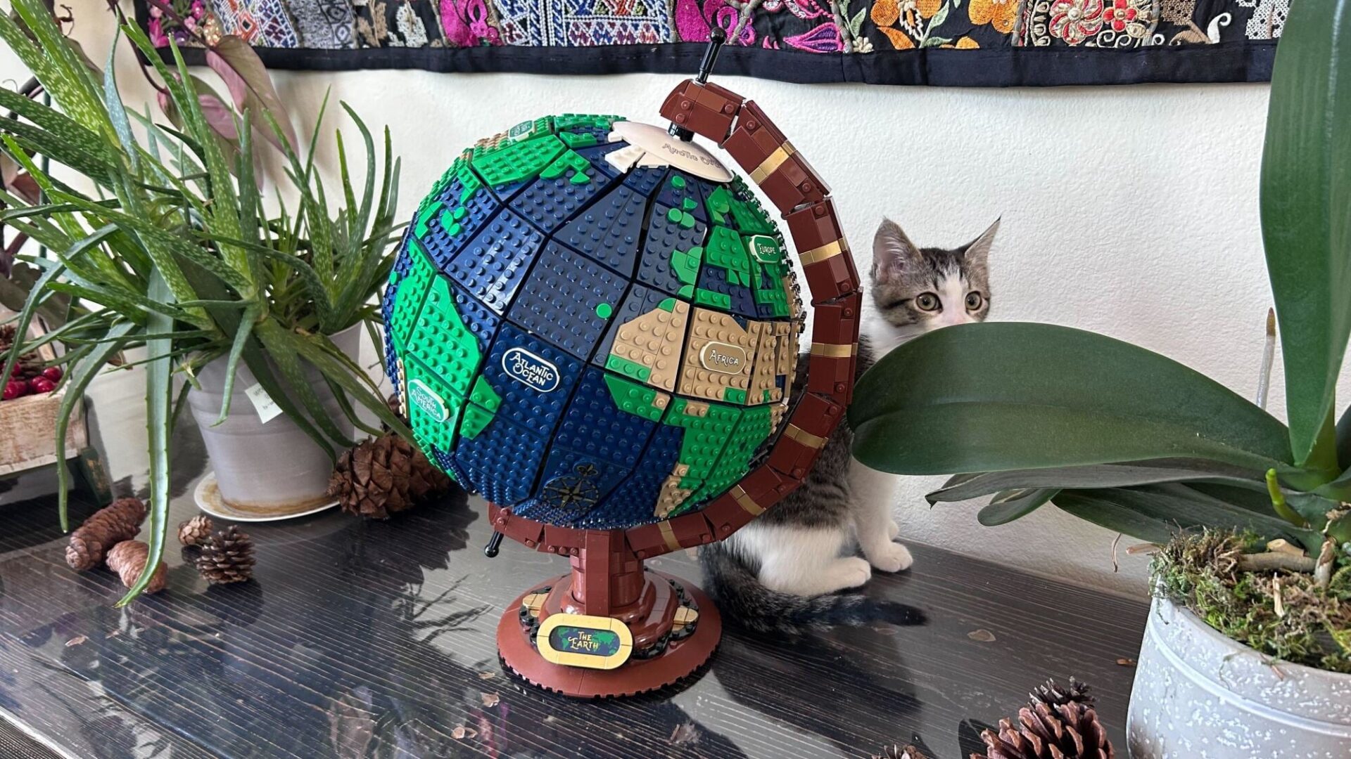 lego globe on sideboard next to plants and kitten
