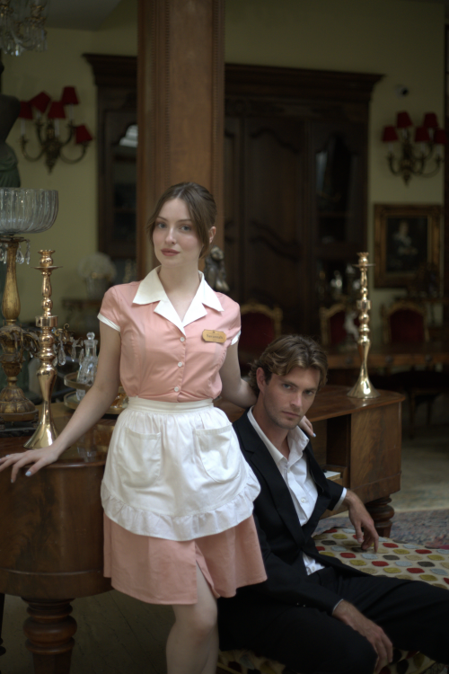 A womam in a maid uniform and a man in a suit pose for a photo