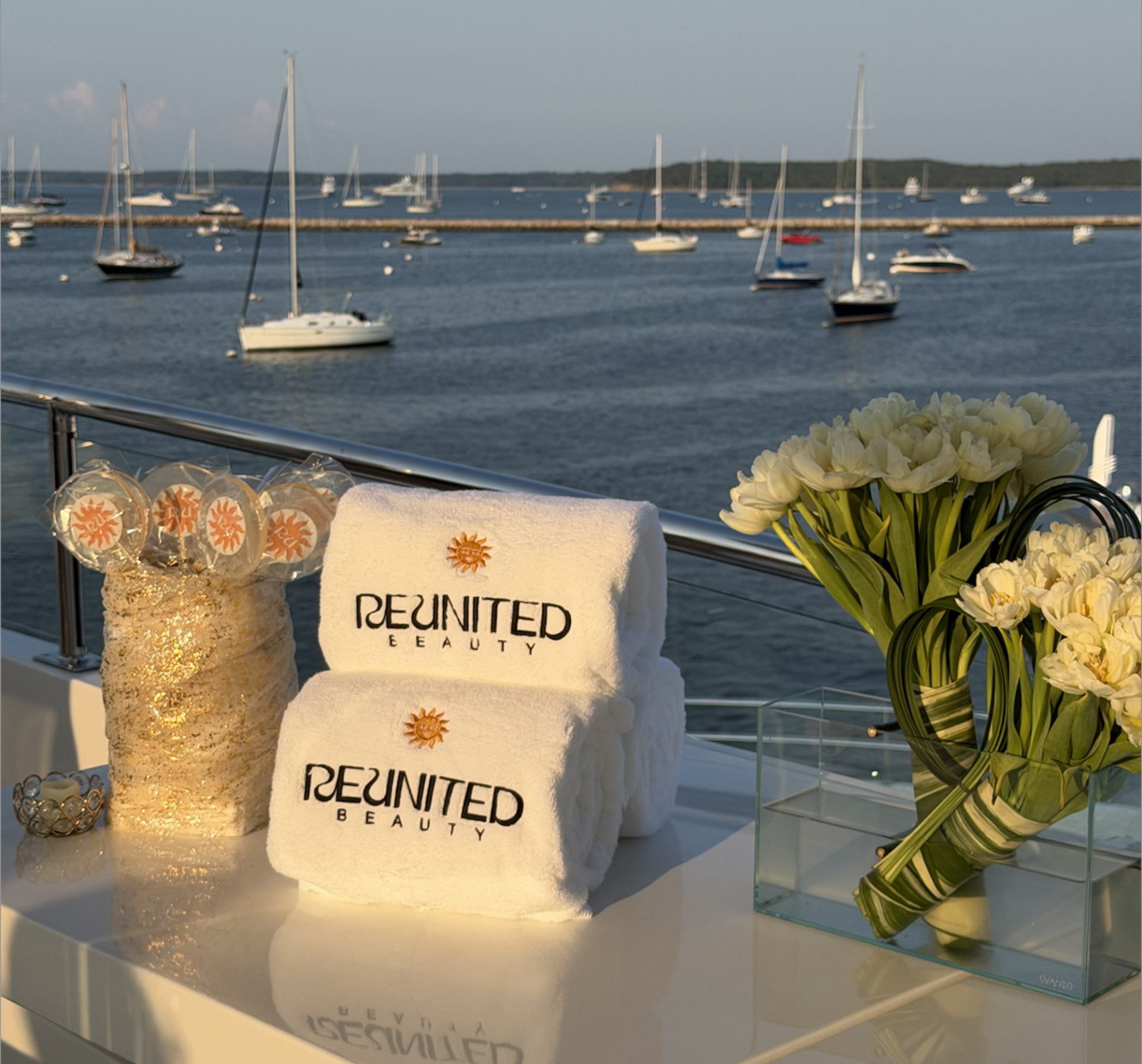Reunited Beauty branded towels in front of a body of water with sailboats