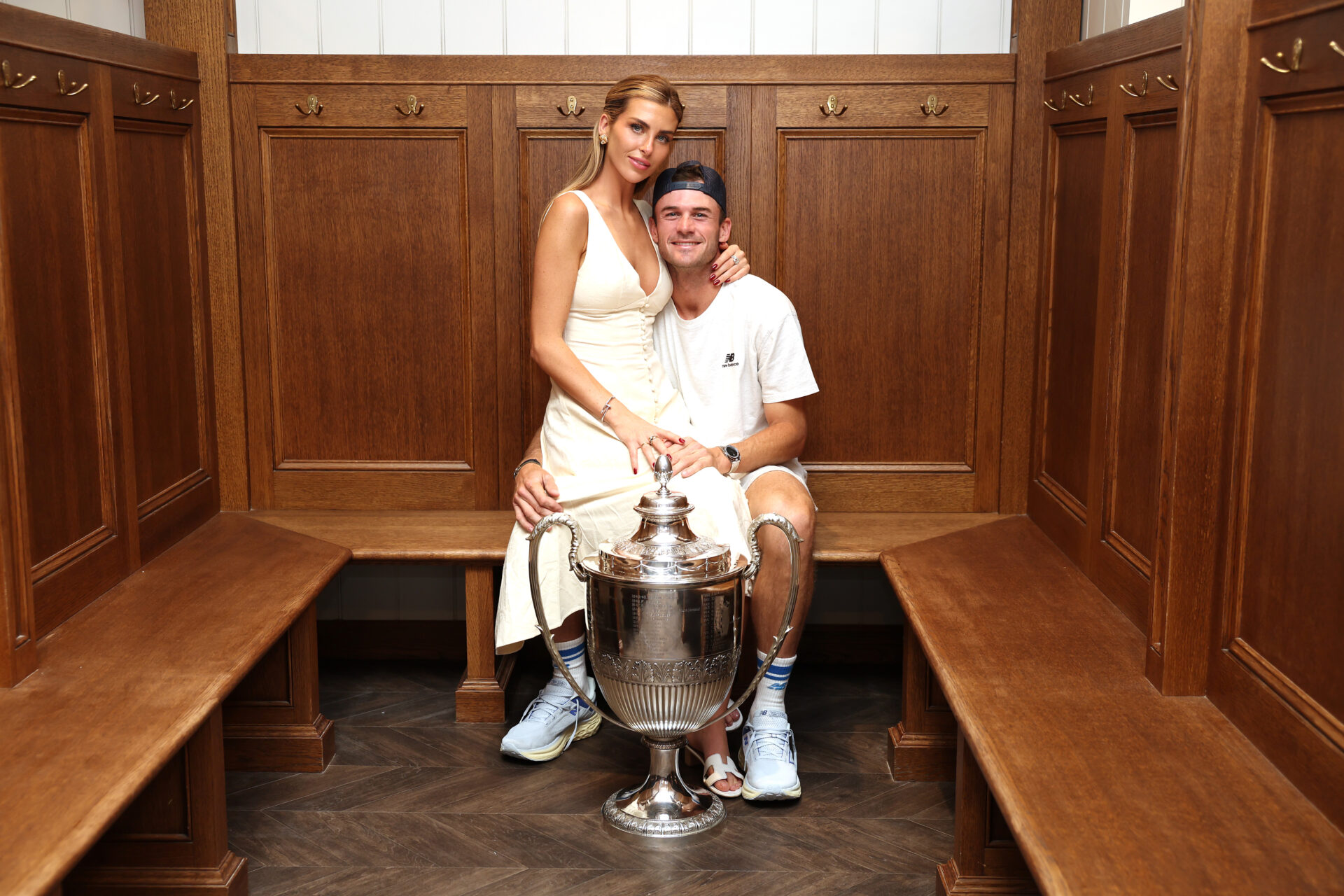 Tommy Paul and Paige Lorenze posing with the cinch Championships 2024 winners trophy in the locker room at Queen's Club in London