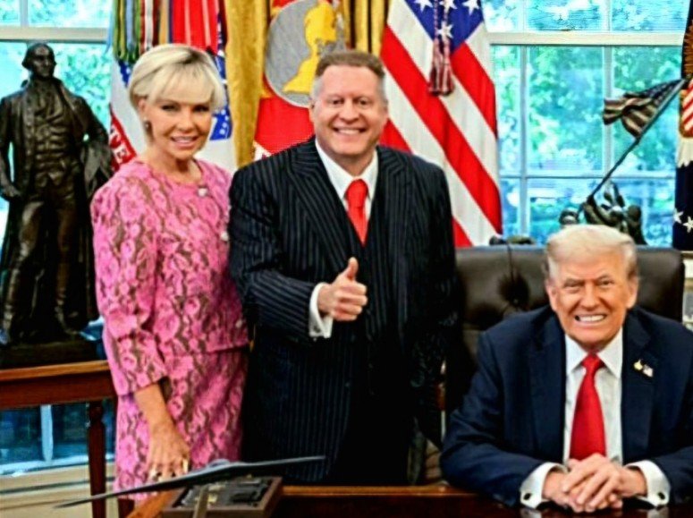 Three individuals pose together in the Oval Office, with flags and a statue in the background, capturing a moment of celebration and camaraderie.