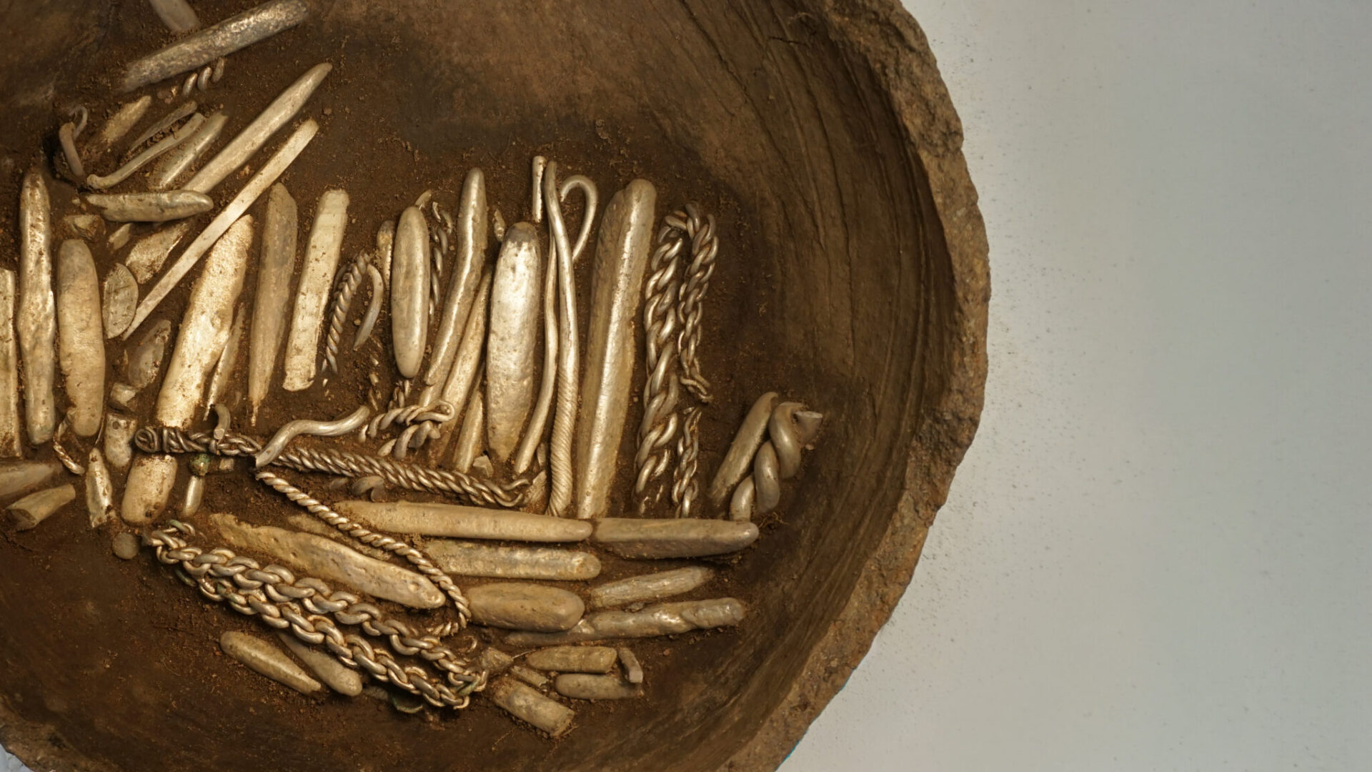 A close up of metal items from a Viking hoard against clean surface