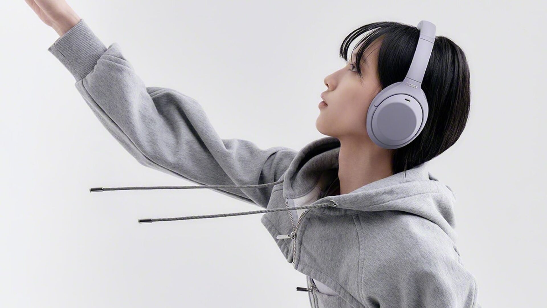 person wearing purple sony headphones reaching their arm out