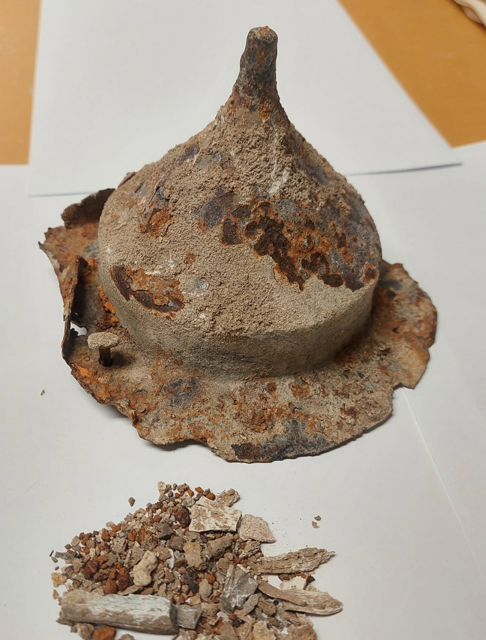 A cone-shaped stone container is full of gray ashes, sitting on a white surface.