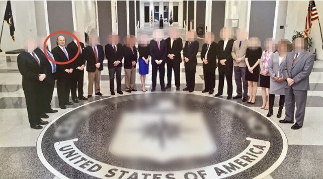 Group photo of officials standing in the lobby of the CIA headquarters, featuring the agency's seal on the floor.